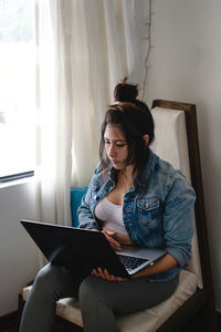 Young woman using mobile phone at home