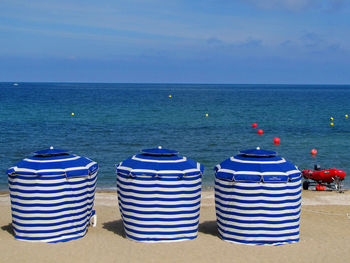 Deck chairs on beach against sky