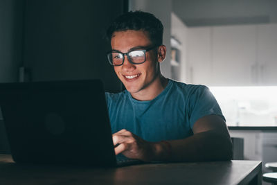 Portrait of young man using laptop while sitting on table