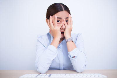 Portrait of woman sitting on table against wall