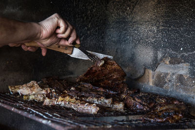 Close-up of person preparing food on barbecue grill