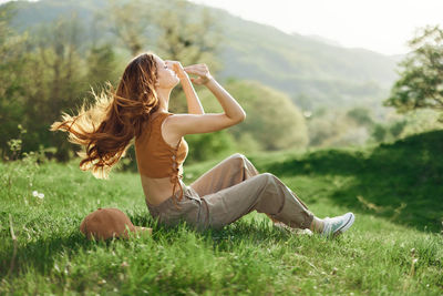 Side view of woman sitting on grassy field