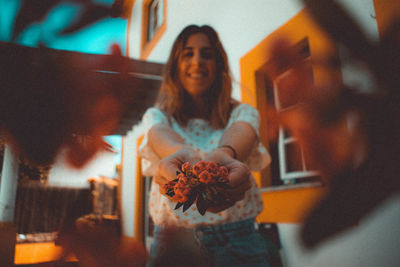 Portrait of young woman holding flowers at home