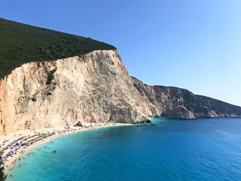 Scenic view of sea by cliff against clear blue sky