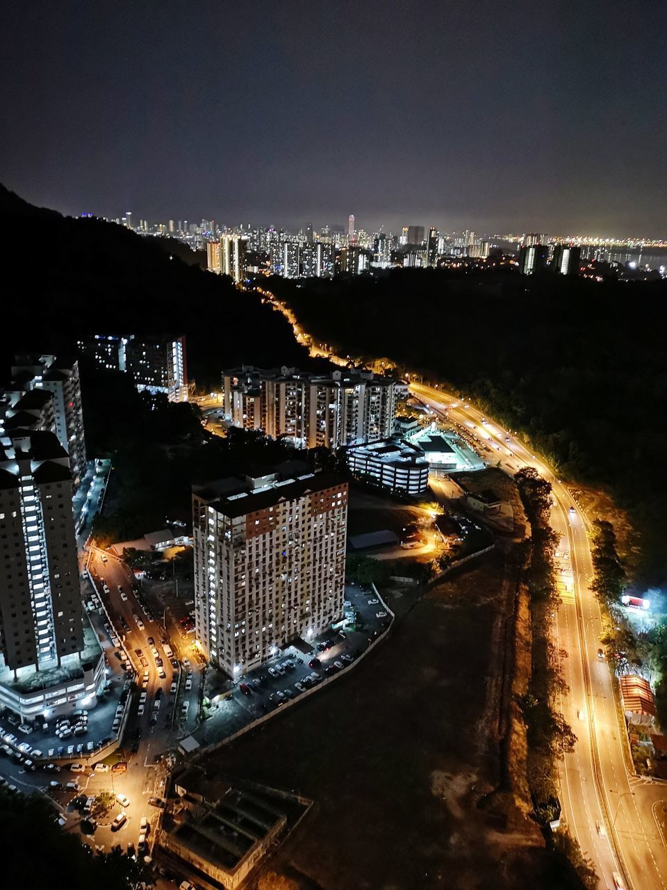 HIGH ANGLE VIEW OF ILLUMINATED ROAD AMIDST BUILDINGS IN CITY AT NIGHT