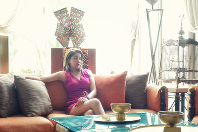 Young woman sitting on sofa at home