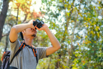 Man looking through binocular at forest