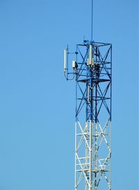 Low angle view of communications tower against clear blue sky