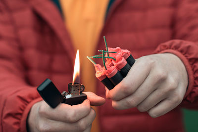 Midsection of person holding lighter and bomb