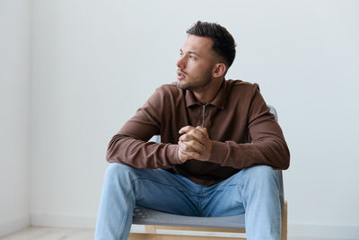 Young man sitting on sofa against wall