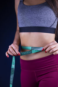 Midsection of woman standing against black background