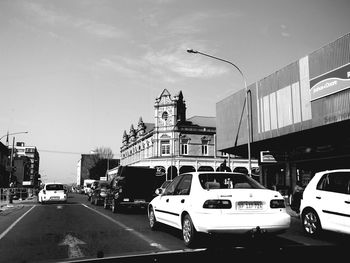 Cars on city street against sky