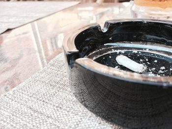 Close-up of cigarette butt in ashtray on table