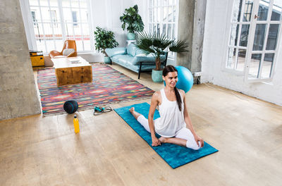 Full length of woman sitting on wooden floor