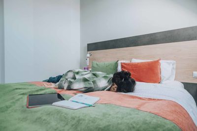 Student collapses face-down on bed, overwhelmed by demands of study, taking breaks to avoid burnout