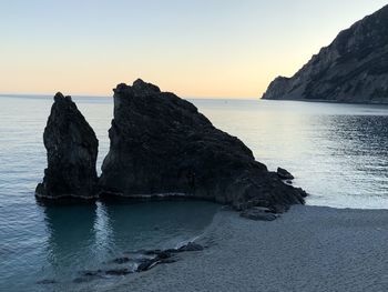 Rock formation on sea against sky during sunset