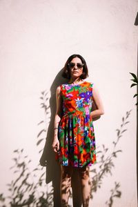 Portrait of woman in colorful dress standing by wall
