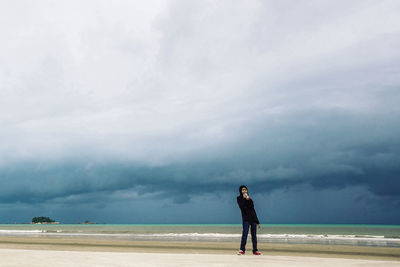 View of woman standing on beach against sky