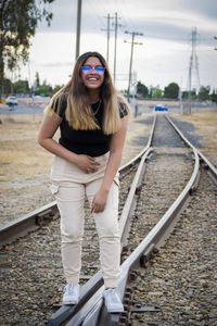 Full length of smiling young woman on railroad tracks