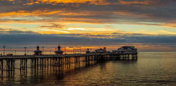 Pier over sea against sky during sunset