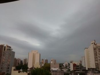 Buildings in city against cloudy sky