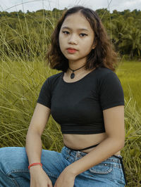 Portrait of beautiful young woman sitting on field