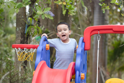 Portrait of happy boy on slide at playground