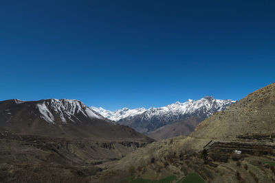 Scenic view of snowcapped mountains against clear blue sky