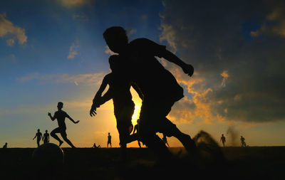 Silhouette people on landscape against sunset