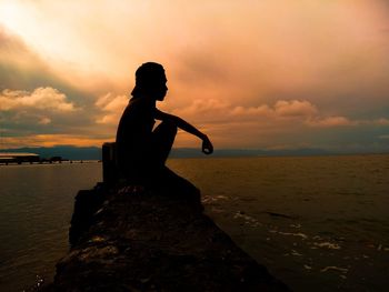 Man looking at sea against sky during sunset
