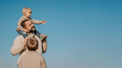 Low angle view of father with kids against sky