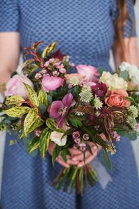 Midsection of woman holding bouquet of flowering plant