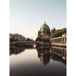 Reflection of building in river against clear sky