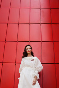 Full length portrait of girl standing against wall