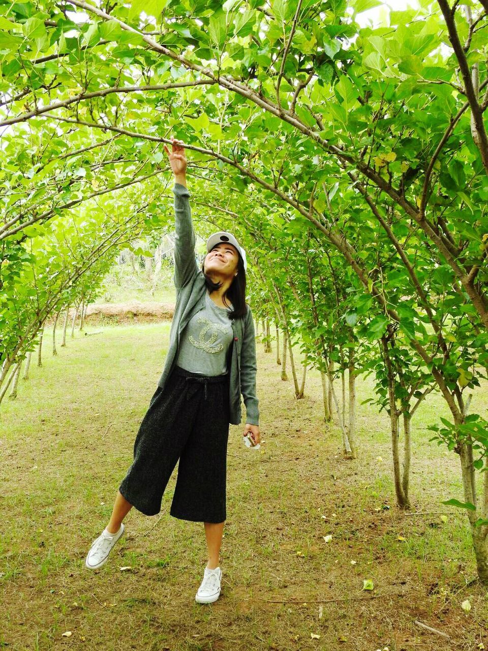 one person, one woman only, only women, full length, adults only, tree, standing, people, nature, green color, grass, young adult, happiness, arms raised, adult, one young woman only, outdoors, human arm, human body part, day, freshness, cheerful