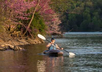 Man rowing boat in lake against trees