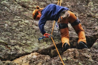 Full length of woman climbing on rock