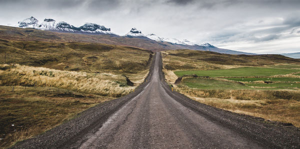 Road amidst field against sky