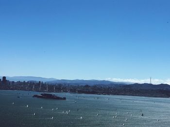 View of city at waterfront against blue sky