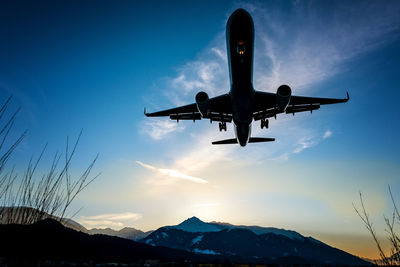 Silhouette airplane flying against sky during sunset