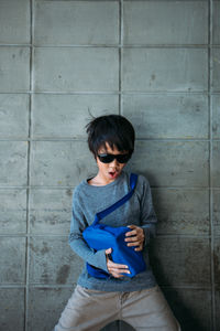 Boy carrying bag while standing against wall