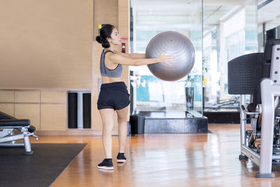 Full length of woman exercising with fitness ball in gym