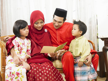 Family reading greeting card on sofa at home during celebration