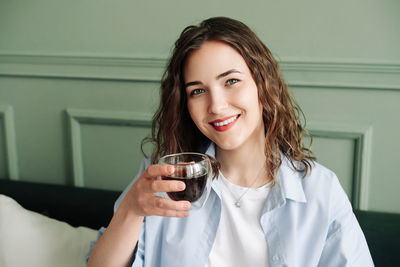 Portrait of young woman having drink at home