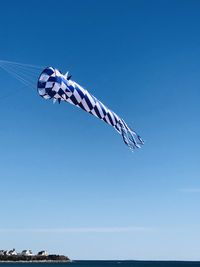 Low angle view of wind sock against clear blue sky