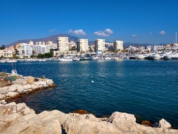 Sea by buildings against blue sky