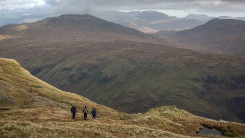 Rear view of hikers on mountain against sky