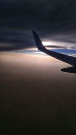 Airplane flying in sky at sunset