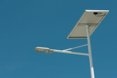Low angle view of solar panel connected to street light against clear blue sky