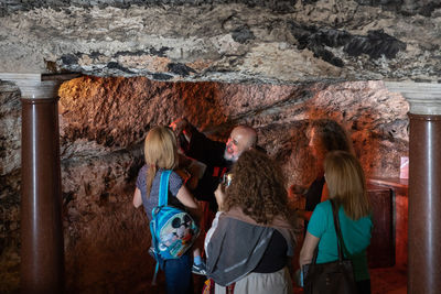 Rear view of women standing against wall